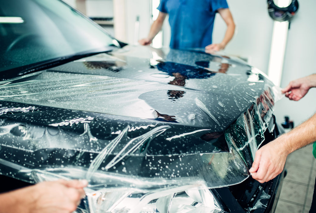 paint protection being placed on a car by 3 technicians