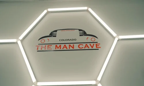 the Man Cave Colorado logo on a wall surrounded by bar lights